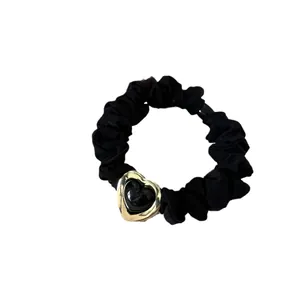Coletero elegante de satén negro con colgante de corazón dorado sobre fondo blanco