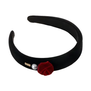 Velvet headband with red rose flower, pearl accent and gold brand tag on white base