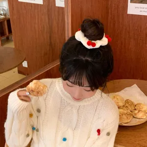 Cute white plush hair scrunchie with red cherry details on a stylish bun hairstyle