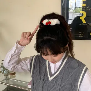 White fluffy scrunchie with red cherry accent worn on a ponytail in a cozy setting