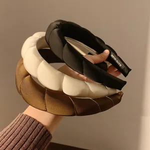 Tre cerchietti imbottiti in raso nero, crema e caramello con un elegante effetto puffy