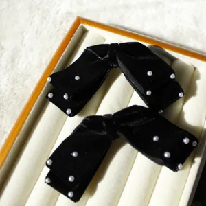 Details von eleganten schwarzen Samt-Haarspangen mit Perlen auf einem Display-Tablett