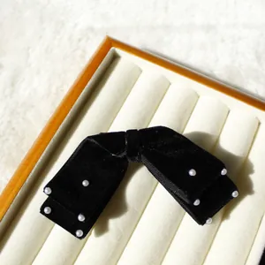 Detailaufnahme der schwarzen Samtschleife mit weißen Kunstperlen für elegantes Haarstyling