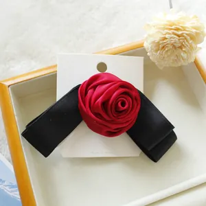 Elegante fermaglio per capelli con rosa di raso rosso e fiocco nero su carta
