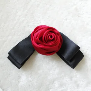 Dettaglio di una rosa in raso rosso su un fiocco nero per capelli con texture di lusso