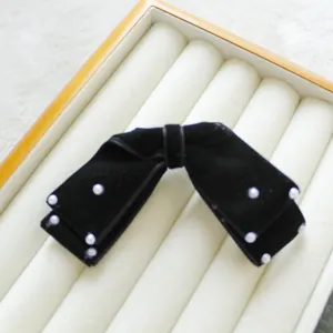 Eleganter schwarzer Samt-Haarclip mit Perlen auf einer weichen Display-Box