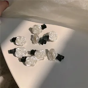 Détail de huit pinces à cheveux roses en résine blanc nacré sur un fond de tulle doux