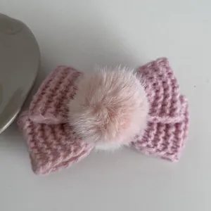 Détail de la pince à cheveux nœud rose tricoté avec pompon et texture tissée