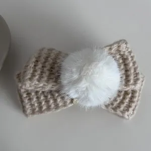 Détail de la barrette à nœud tricoté beige avec pompon blanc et texture gaufrée