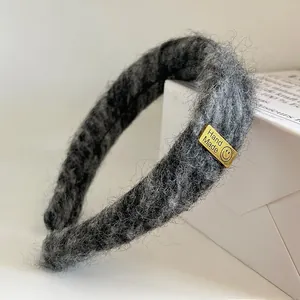 Makroaufnahme des dunkelgrauen Samt-Haarreifs mit goldenem Hand Made Metall-Etikett