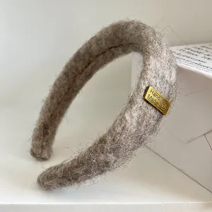Detail des grauen Samt-Stirnbands mit handgefertigtem Metallemblem und weichem Plüsch