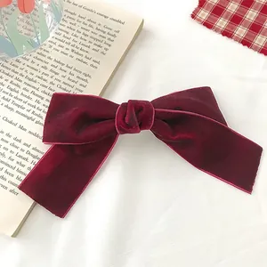Close-up of a vintage dark red velvet bow hair clip on a retro book background