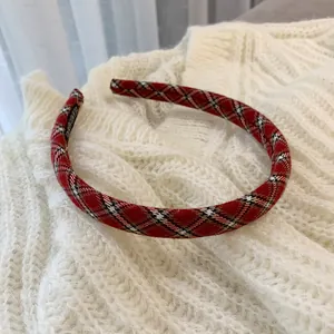 Detail of red plaid headband with handmade label on soft white knitted sweater background
