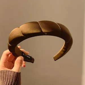Dettaglio del cerchietto imbottito in raso bronzo con etichetta fatta a mano