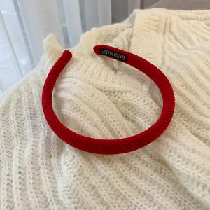Detail of red corduroy headband with handmade label on soft white knit background