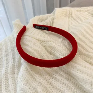 Close-up of red velvet headband with hand-made label on a knitted sweater background