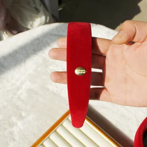 Eleganter Haarreif aus rotem Samt mit rundem goldenem Metall-Logo und Gravur