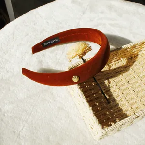 Maillard style padded velvet headband in warm pumpkin red with golden metal tag