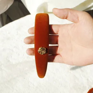 Vintage orange velvet headband with golden camellia flower detail for an elegant hair style