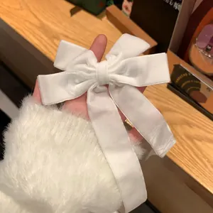 Détail d'une barrette à cheveux nœud en velours blanc crème avec de longs rubans