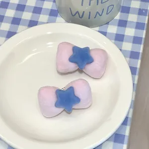 Close-up of pink velvet bow hair clips with blue stars in a ceramic dish display