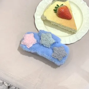 Dettaglio della pinza per capelli in peluche azzurro con morbide stelle colorate