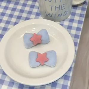 Detail of soft blue velvet bow hair clips with pink star on a white porcelain dish