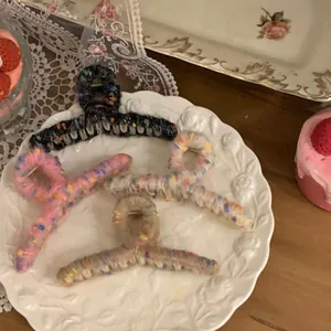 Set of four colorful tweed knit hair claws displayed on an elegant ceramic plate