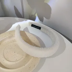 Detail of white textured seersucker headband with handmade label on a ceramic tray