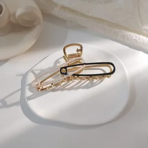 Detail van metalen haarklem in paperclip-ontwerp met zwart en beige emaille afwerking