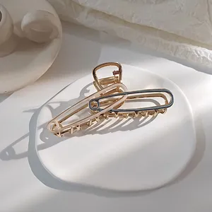 Detail van een grote gouden metalen haarklem met beige en marineblauwe accenten