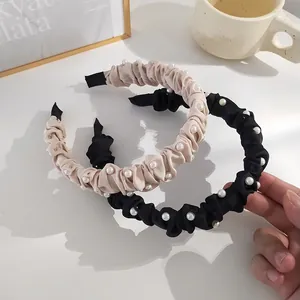 Détail de serre-têtes plissés élégants avec perles en satin beige et noir chic