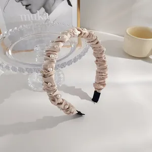Détails du serre-tête beige à nœud avec perles élégantes et texture de tissu plissé