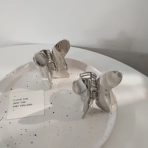 Macro shot of silver butterfly metal hair claw clips with polished finish on a ceramic plate
