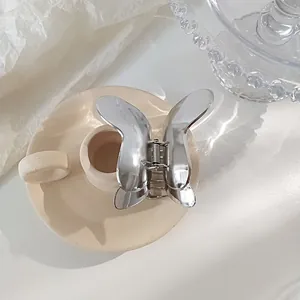 Close-up of silver butterfly hair claw clip with metallic finish on ceramic decor