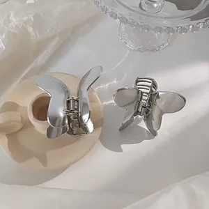 Detailed macro view of two silver metal butterfly hair claws on a ceramic tray