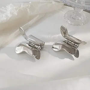 Elegant silver metal butterfly hair claws set on a white textured background