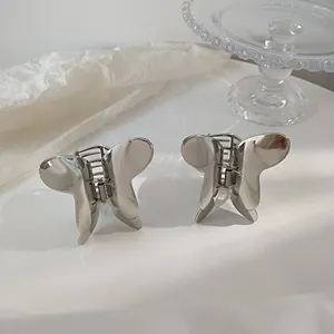 Macro detail of silver metal butterfly hair clips with polished mirror finish and spring