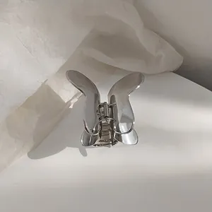 Macro view of silver butterfly metal hair claw clip with a high-polished mirror finish