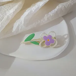 Detail shot of a purple floral duckbill hair clip with pearls on a ceramic plate