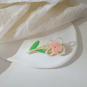 Detail of pink flower hair clip with pearls on a textured white display background