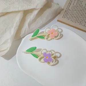Detailed view of handmade Morandi flower hair clips with pearls and green leaves