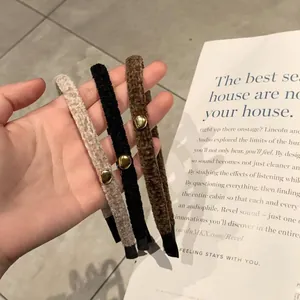 Three plush hairbands in beige, black, and coffee colors with a single gold bead accent