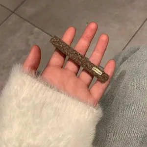 Close-up of brown faux shearling hair clip with LOVEDAYS tag being held in hand