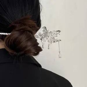 Silver butterfly hair pin with tassel and white charms worn on a dark brown hair bun