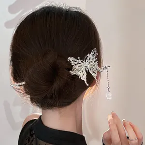 Detail of silver liquid metal butterfly hair pin with textured wings and bell tassel