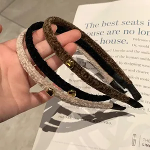 Three plush lamb wool headbands in beige, black, and brown with gold metal clips