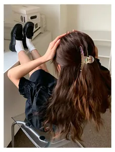Nahaufnahme einer großen Haarspange mit Aurora-Effekt im braunen welligen Haar