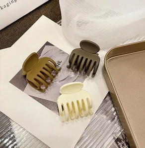 Macro view of matte resin hair claws in cream, caramel brown, and olive green colors