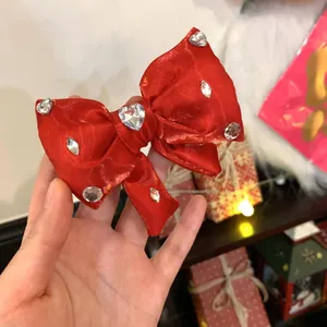 Dettaglio fermaglio a fiocco in raso rosso con un cuore di strass scintillante al centro